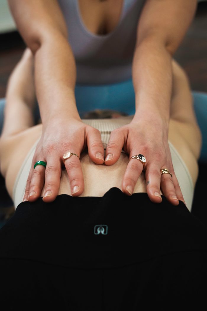 Yoga teacher assisting a student in a New York studio for enhanced well-being and relaxation.
