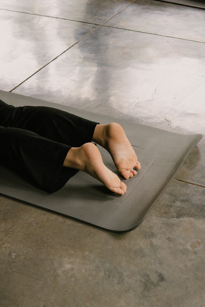 Feet on a gray yoga mat during an indoor yoga session, focused on simplicity.