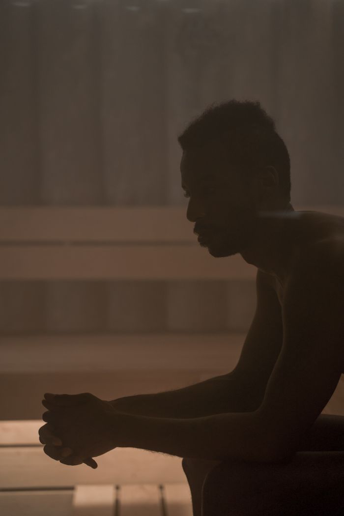 Silhouette of a man relaxing in a misty sauna, promoting wellness.